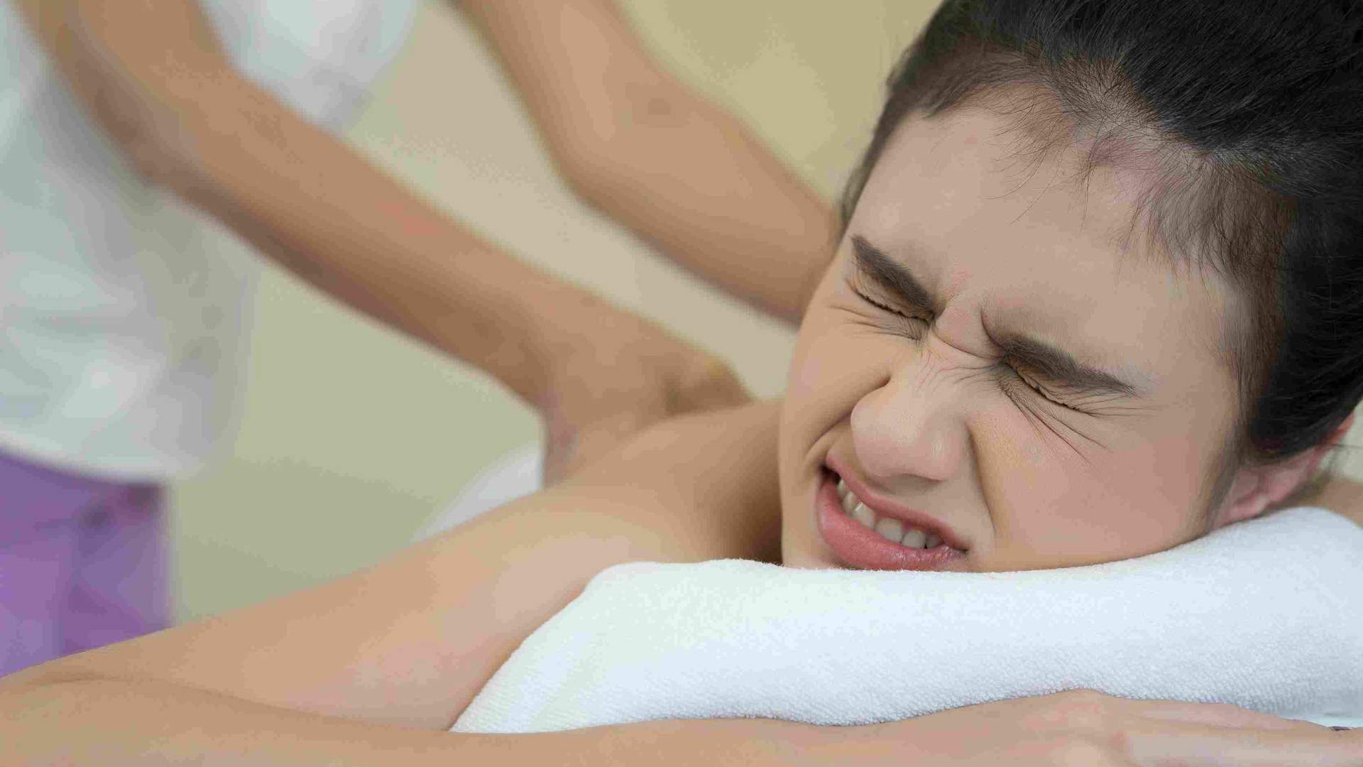 Wanita meringis saat menjalani body massage untuk membantu meredakan otot tegang.